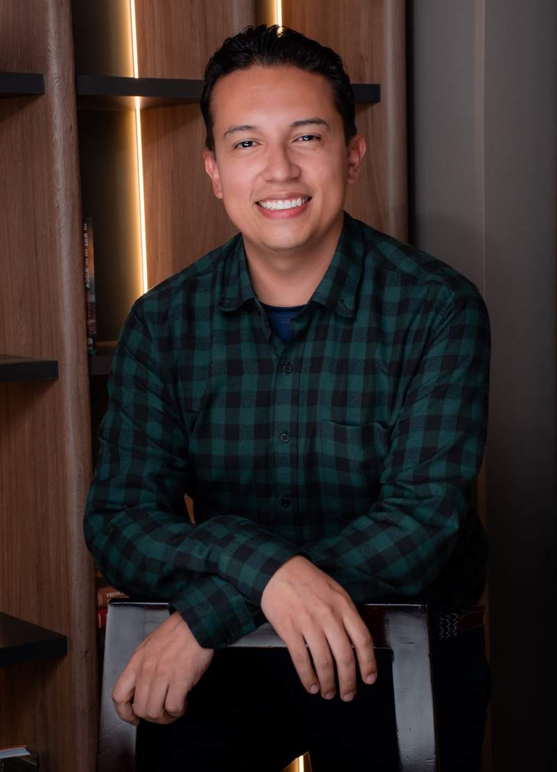 Christian F. Rojas apoyado en el respaldo de una silla, sonriendo.